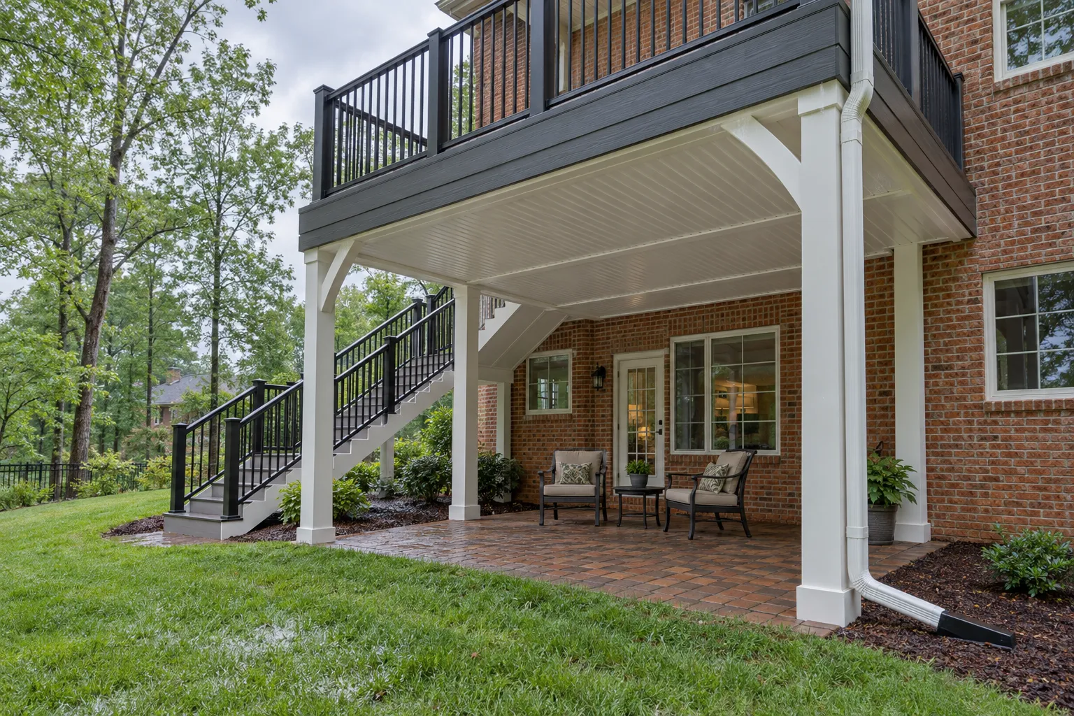 Illustrative drainage ceiling, gutter and downspout beneath an elevated deck with a sheltered sitting area